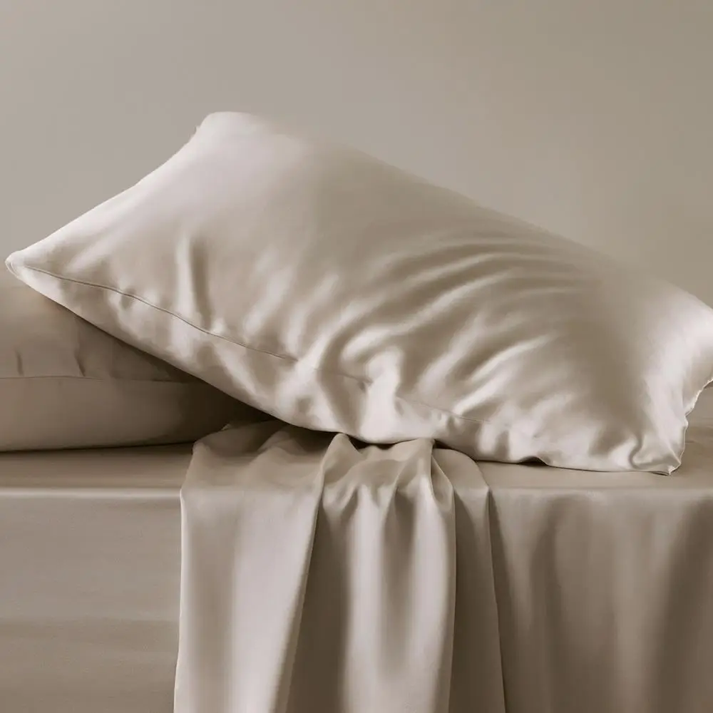 Zwei elfenbeinfarbene Seidenkissenbezüge auf einem Bett mit passendem Bettlaken