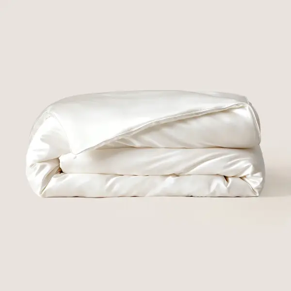 Couette en soie de mûrier ivoire pliée sur fond uni