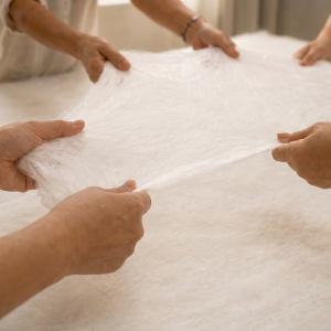 Mains étirant à la main une couche de nappe de soie de mûrier