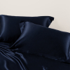 Detailopname van donker marineblauwe zijden kussenslopen in een slaapkamer