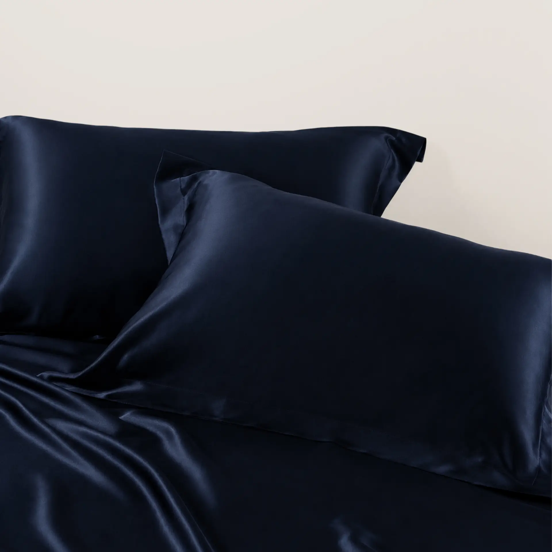 Detailopname van donker marineblauwe zijden kussenslopen in een slaapkamer