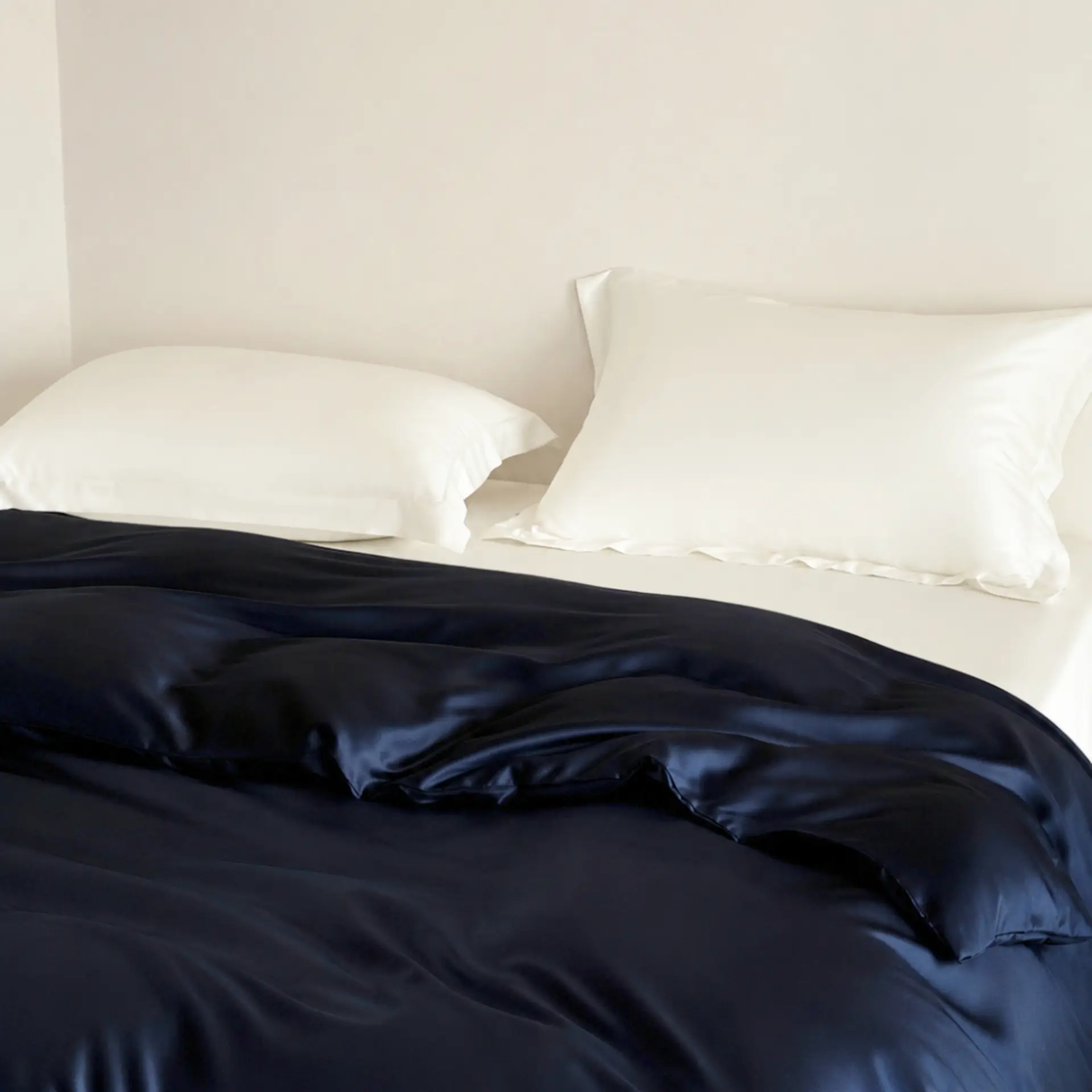 Marineblauwe beddengoedset van moerbeizijde, gestyled op een bed.