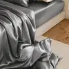 Des draps en soie de mûrier grise drapés sur le côté d'un lit