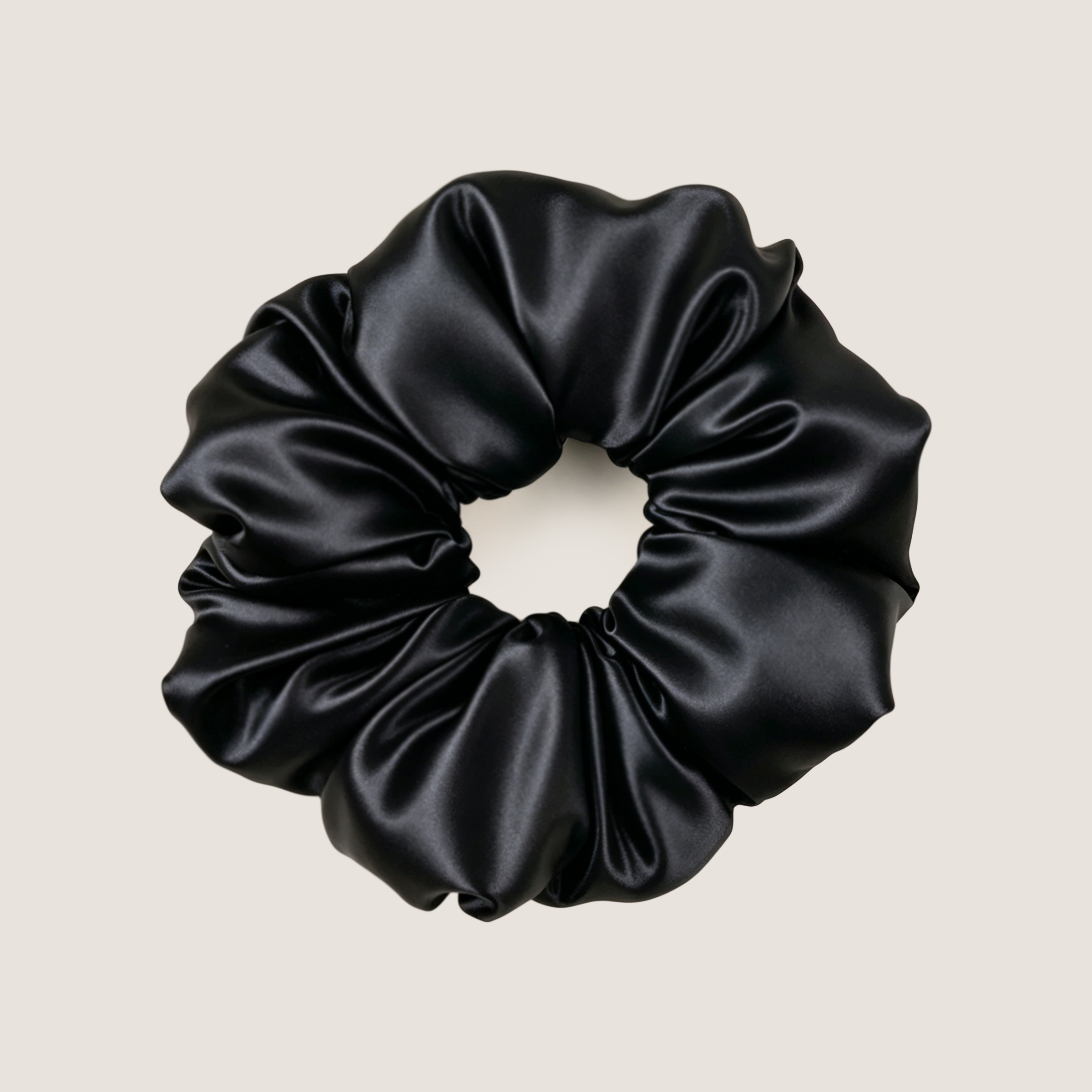 Zwarte moerbeizijden scrunchie om mee te slapen, op een effen achtergrond.