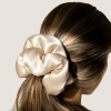 Oversized champagnekleurige zijden scrunchie die lang bruin haar bijeenhoudt