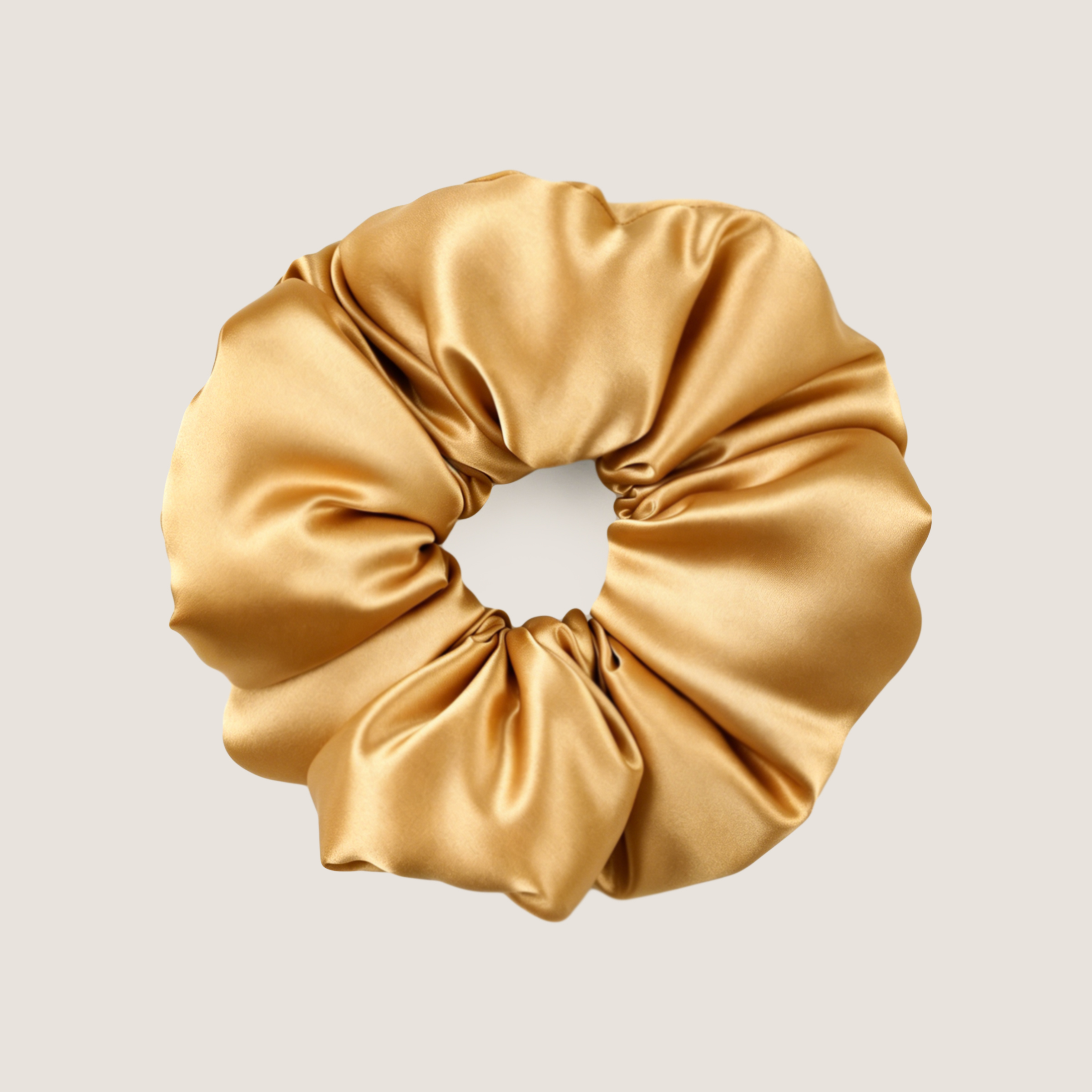 Gouden moerbeizijden scrunchie om mee te slapen, op een effen achtergrond.