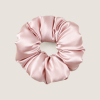 Oversized zachtroze scrunchie van moerbeizijde op een zachtbeige achtergrond