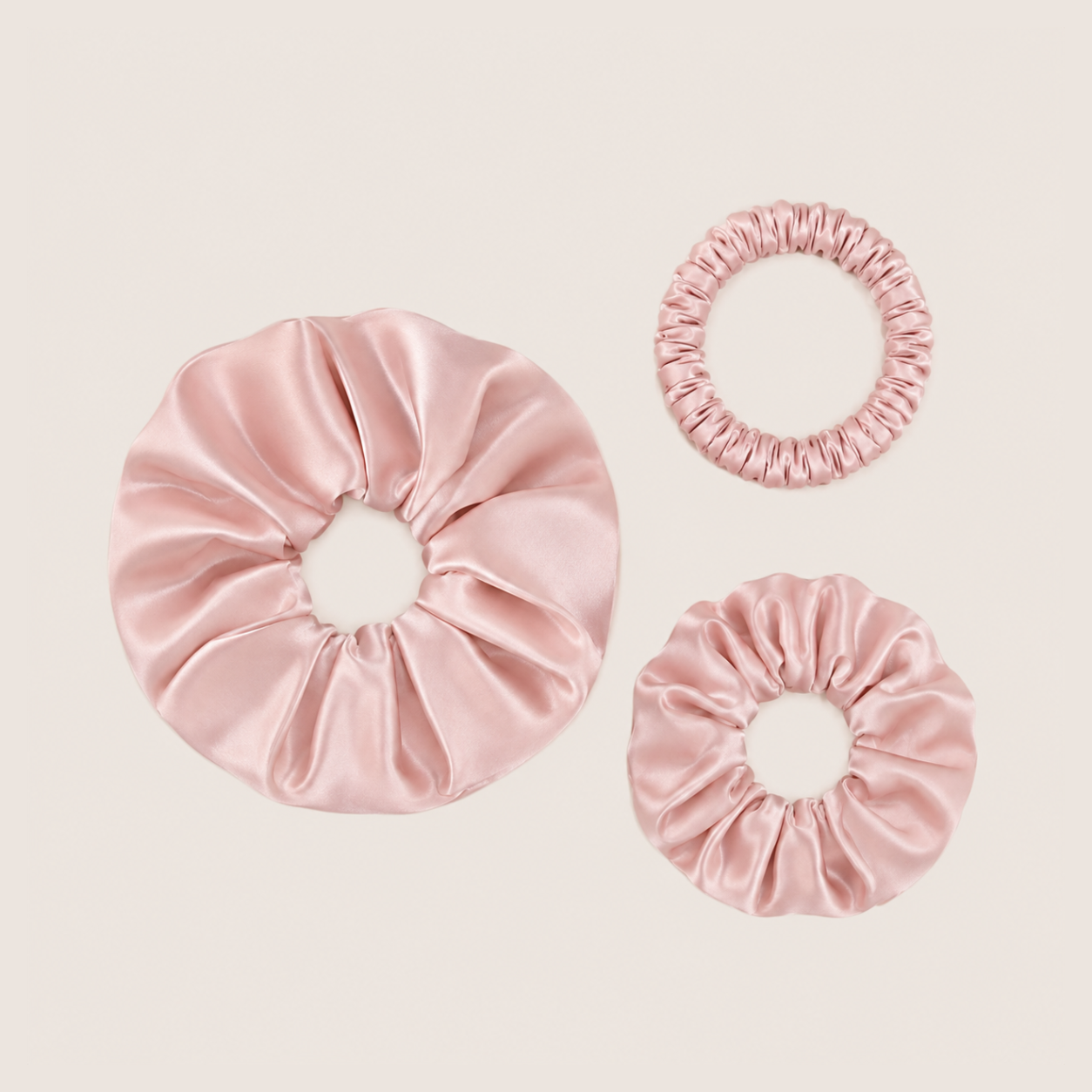 Set roze scrunchies van moerbeizijde in drie maten op een neutrale achtergrond
