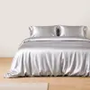 Zilverkleurige zijden kussenslopen op een bed