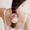 Vrouw met roze en witte scrunchies van moerbeizijde in de vorm van rozen in een gevlochten paardenstaart.