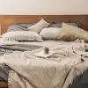 Fundas de cojín Sensoire de lino francés oliva y natural sobre una cama de lino gris