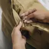 Primer plano al abrochar una funda de cojín Sensoire de lino francés oliva