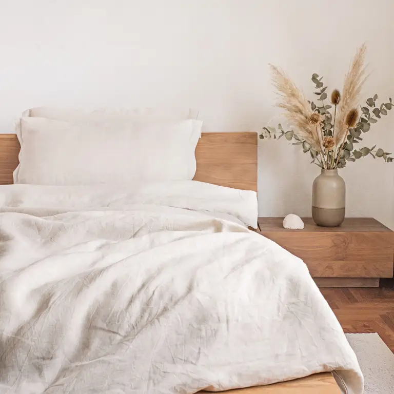 Bettwäsche-Set aus Naturleinen auf einem Eichenbett in einem ruhigen, sonnigen Schlafzimmer