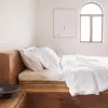 Weiße Leinenbettwäsche und Kissen auf einem hölzernen Plattformbett