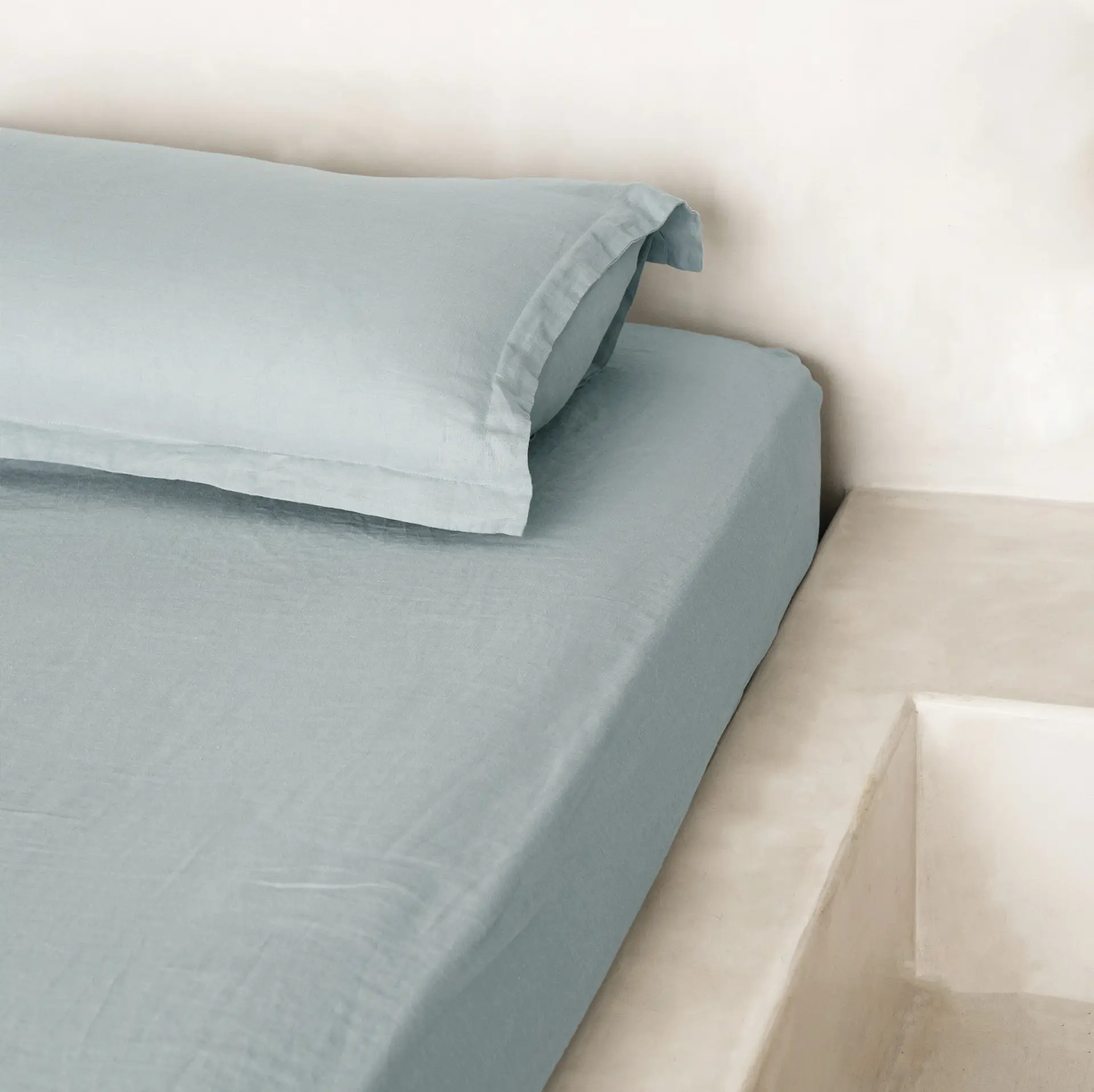 Bettwäsche aus taubenblauem gewaschenem Leinen in einem ruhigen Schlafzimmer