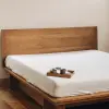Spannbettlaken aus Naturleinen auf einem Holzbett mit Frühstückstablett
