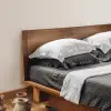 Ein graues Leinenlaken, darüber weiße Kissen, auf einem walnussfarbenen Bett
