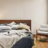 Manta de lino francés Sensoire natural sobre ropa de cama de lino carbón en un dormitorio minimalista