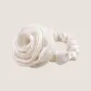Witte scrunchie van moerbeizijde met een sculpturaal rozendetail op een neutrale achtergrond
