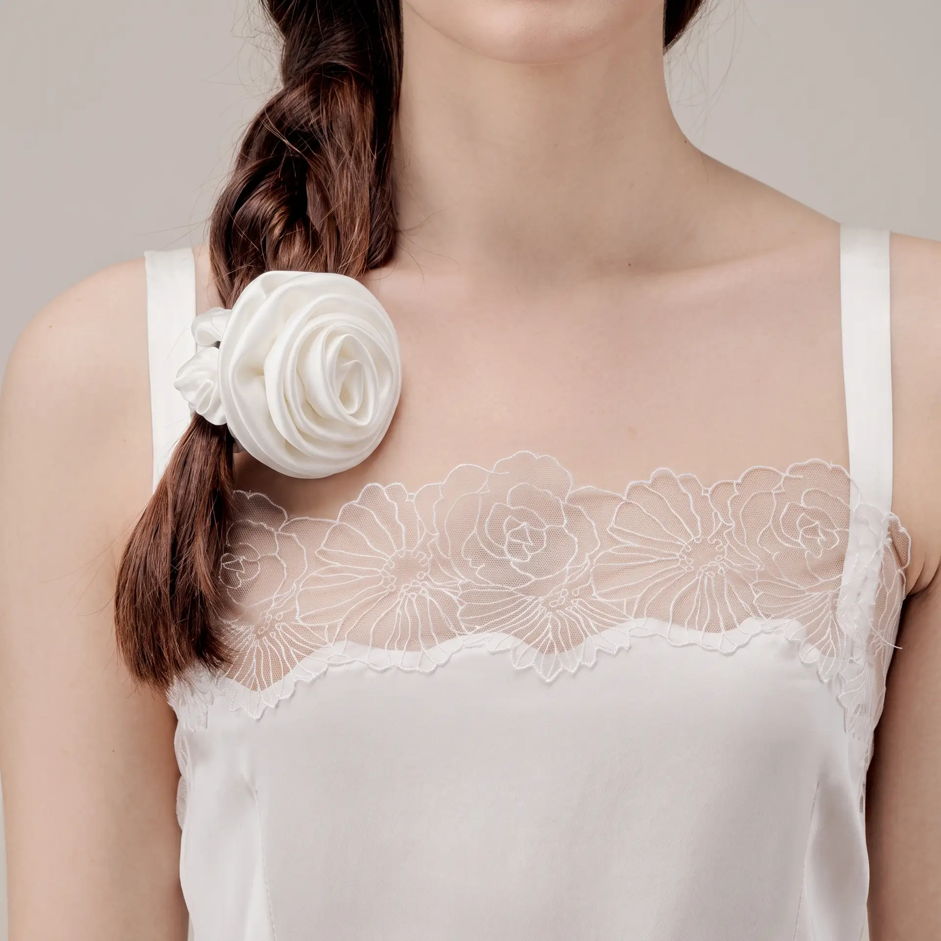 Vrouw met een witte scrunchie van moerbeizijde met rozendetail in een zijvlecht.