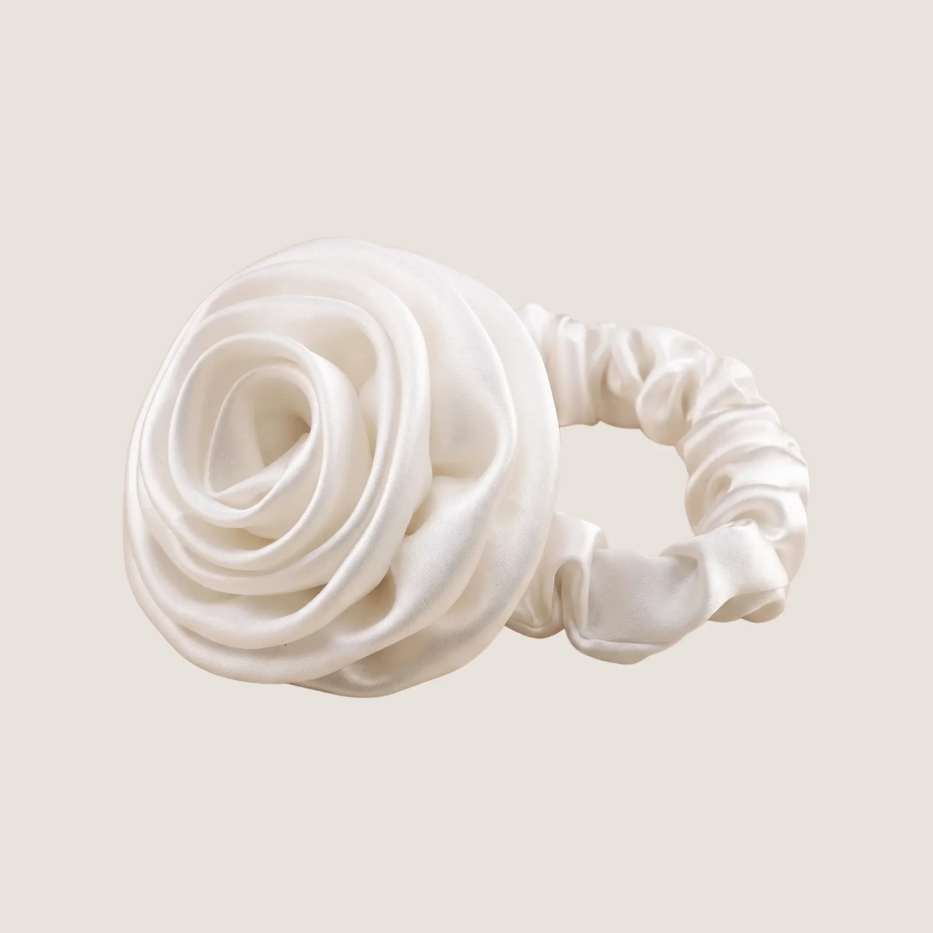 Witte scrunchie van moerbeizijde met een sculpturaal rozendetail op een neutrale achtergrond
