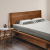 Bettwäsche aus salbeigrünem Bambus-Lyocell auf einem Bett mit hölzernem Kopfteil und einem Nachttisch mit Kerzen.