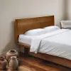 Weiße Bambus-Lyocell-Bettwäsche auf einem Bett mit hölzernem Kopfteil und Terrakotta-Vasen auf dem Boden daneben.