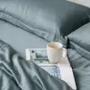 Schieferblaue Kissenbezüge aus Bambus-Lyocell auf Kissen auf einem ordentlich gemachten Bett in einem ruhigen Schlafzimmer.