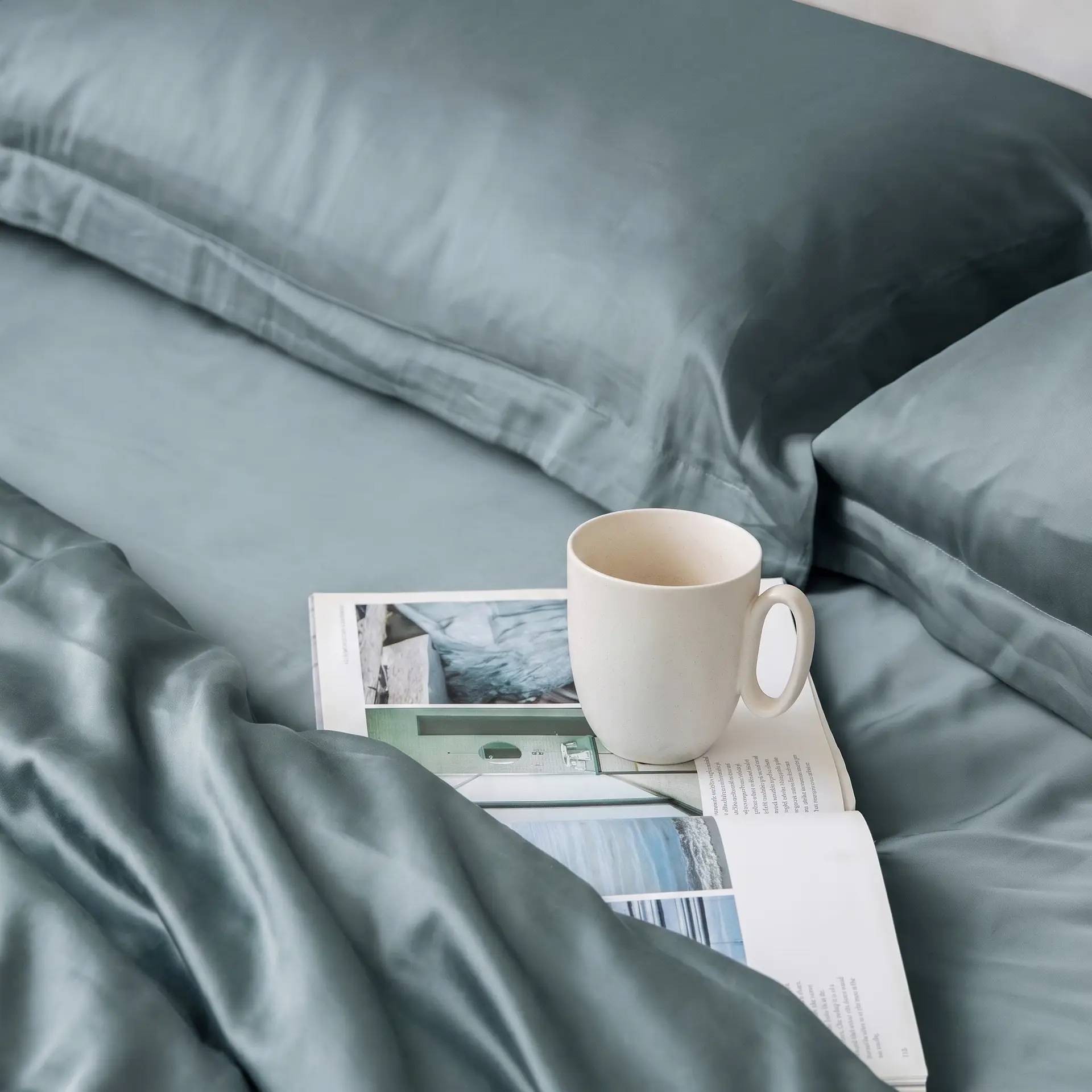 Schieferblaue Kissenbezüge aus Bambus-Lyocell auf Kissen auf einem ordentlich gemachten Bett in einem ruhigen Schlafzimmer.