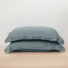 Gefaltete schieferblaue Kissenbezüge aus Bambus-Lyocell vor einem schlichten Studiohintergrund.