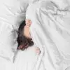 Weiße Kissenbezüge aus Bambus-Lyocell auf einem Bett mit Holzkopfteil in einem hellen Schlafzimmer.