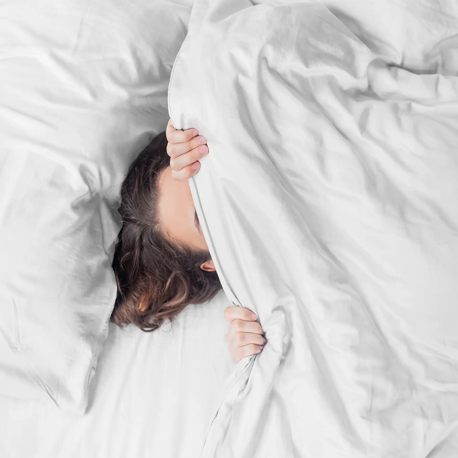 Weiße Kissenbezüge aus Bambus-Lyocell auf einem Bett mit Holzkopfteil in einem hellen Schlafzimmer.