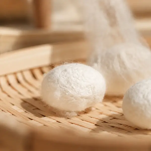 Witte zijdecocons en losse zijdevezels op een rotan dienblad