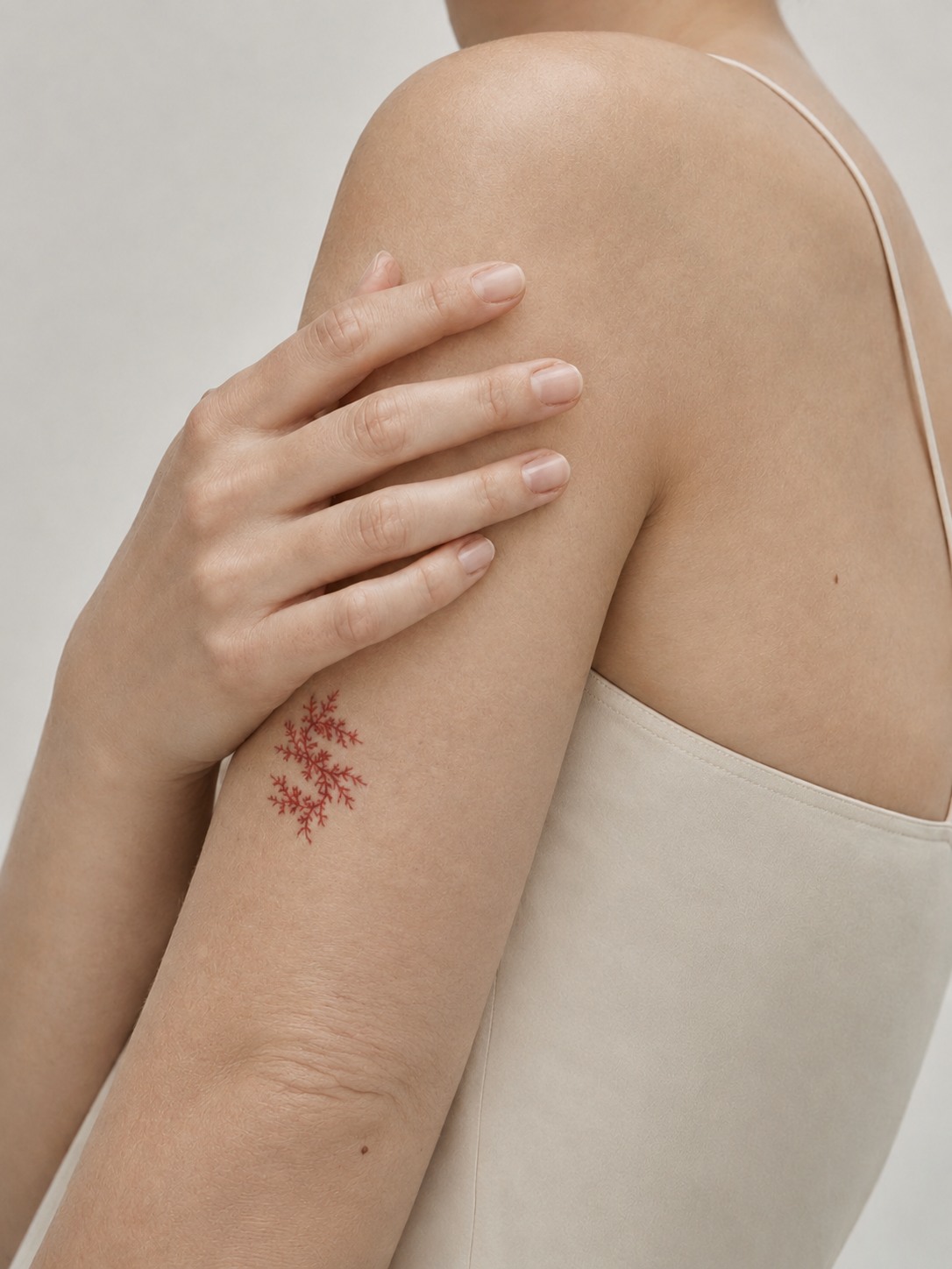 Hand auf einer nackten Schulter über einem elfenbeinfarbenen Trägertop