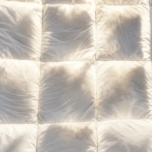 Gros plan sur une couette blanche piquée dans la douce lumière d'une fenêtre