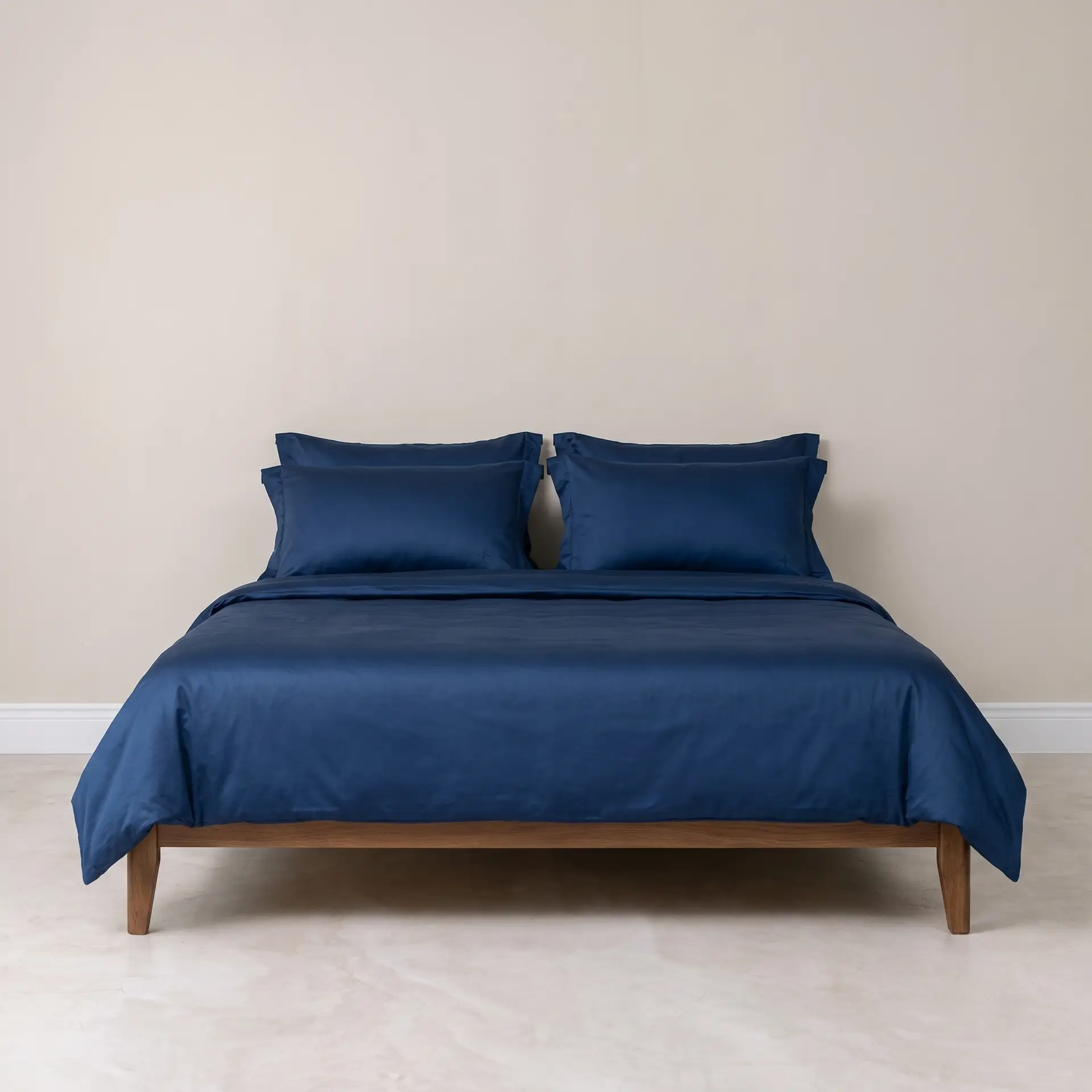Marineblauer Sensoire Bettbezug aus Bambus-Lyocell auf einem niedrigen Holzbett in einem hellen, kargen Raum