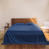 Marineblaues Bambus-Lyocell-Bettlaken von Sensoire auf einem Bett mit Holzkopfteil und Nachttisch
