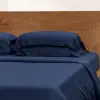 Spannbettlaken und Kissenbezüge aus marineblauem Bambus-Lyocell von Sensoire auf einem Bett mit Holzkopfteil