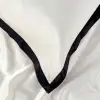 Nahaufnahme glatter weißer Seidenkissenbezüge mit breiter schwarzer Bordüre aus dem Bettwäsche-Set Noir Contour