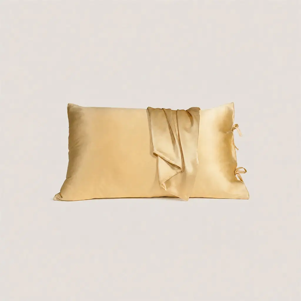 Gouden kussensloop van moerbeizijde met striksluiting, waarbij de flap openvalt om de binnenste strikjes te laten zien.