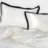 Nahaufnahme glatter weißer Seidenkissenbezüge mit breiter schwarzer Bordüre aus dem Bettwäsche-Set Noir Contour
