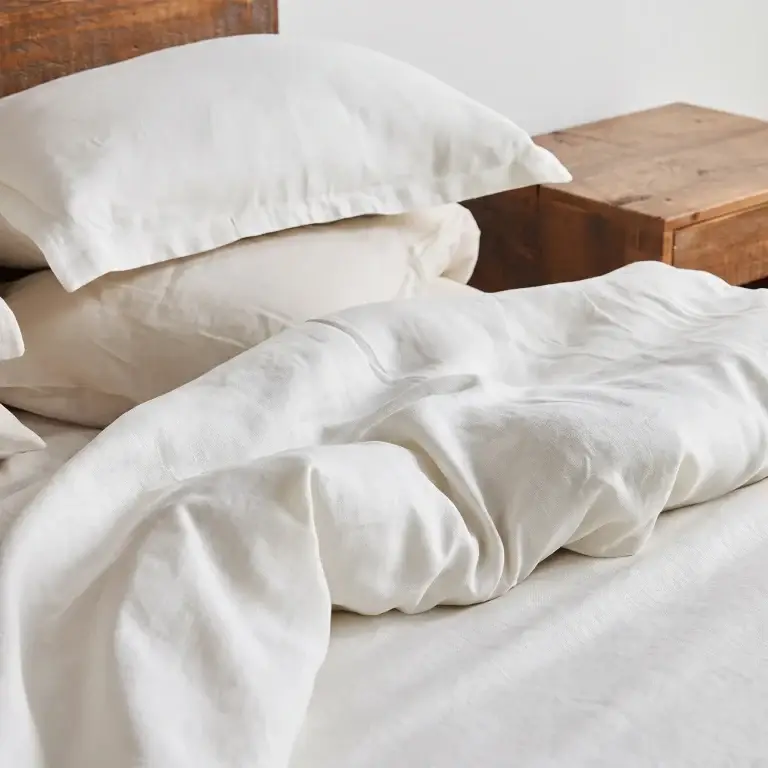 Weiße Kopfkissenbezüge und Bettbezug aus Hanf auf einem ungemachten Bett