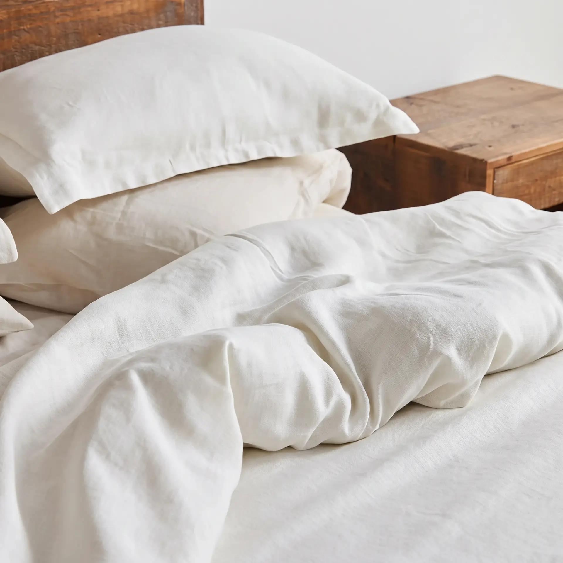 Weiße Kopfkissenbezüge und Bettbezug aus Hanf auf einem ungemachten Bett