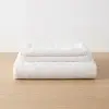 Weißer Bettbezug und zwei Kopfkissenbezüge aus Hanf, auf einem Tisch gestapelt
