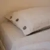 Kopfkissenbezug aus Hanf in Natur mit drei Kokosnussknöpfen auf einem Bett