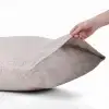 Eine Hand öffnet den Einschlag eines Kopfkissenbezugs aus Hanf in Natur