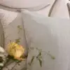 Kopfkissenbezug aus Hanf in Natur mit Hotelverschluss neben einer gelben Rose