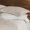 Kopfkissenbezüge aus Hanf mit Hotelverschluss in Natur und Weiß auf einem Holzbett