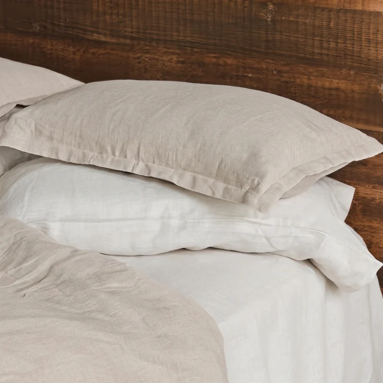 Kopfkissenbezüge aus Hanf mit Hotelverschluss in Natur und Weiß auf einem Holzbett