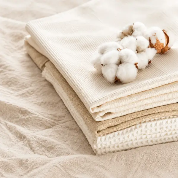 Katoenbollen op een stapel gevouwen crèmekleurig katoenen textiel